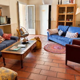Salon commun chaleureux de L’Arbre du Voyageur avec canapés bleus et mobilier coloré