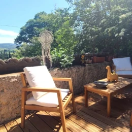 Salon de jardin en bois sur une terrasse ensoleillée avec vue sur les collines de Saint-Jean-de-Fos